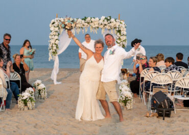 Newlyweds celebrating on beach under floral arch