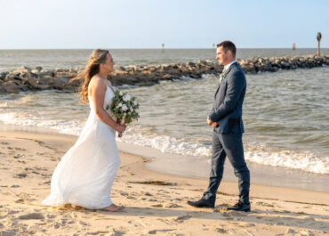 Wedding couple on sandy beach with bouquet