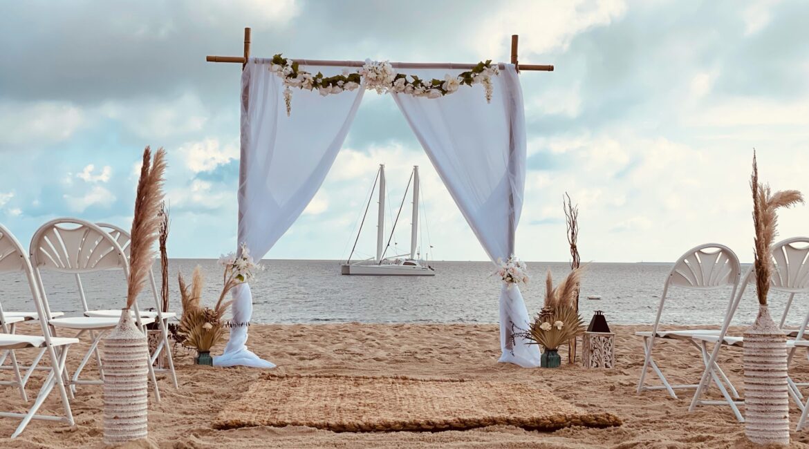 Beach wedding arch with sailboat backdrop